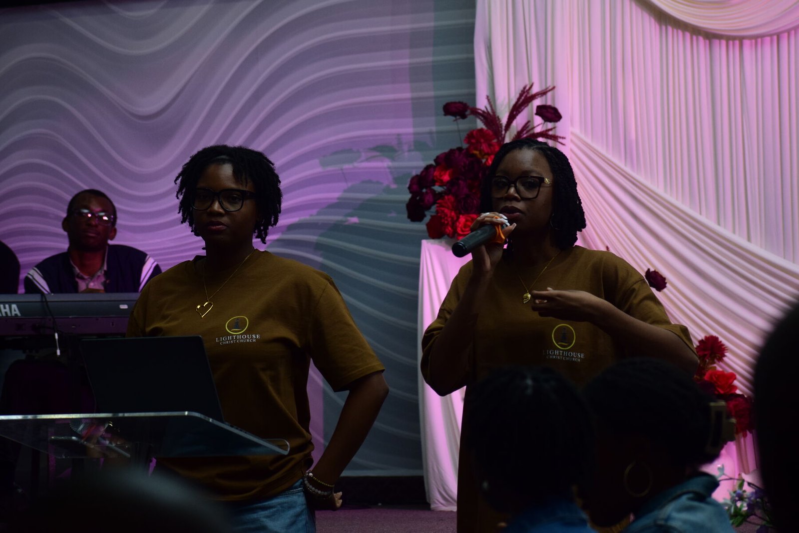Two members of Lighthouse Christ Church in branded tees, one leading with a microphone